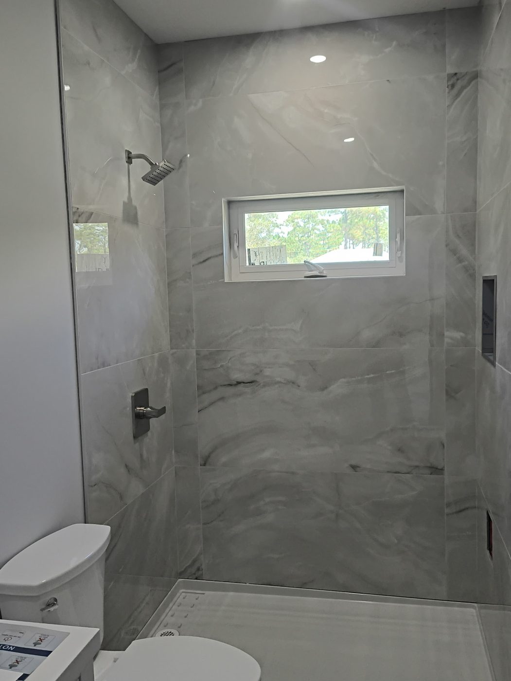 Finished walk-in shower with large-format marble tile and wall-mount rain head