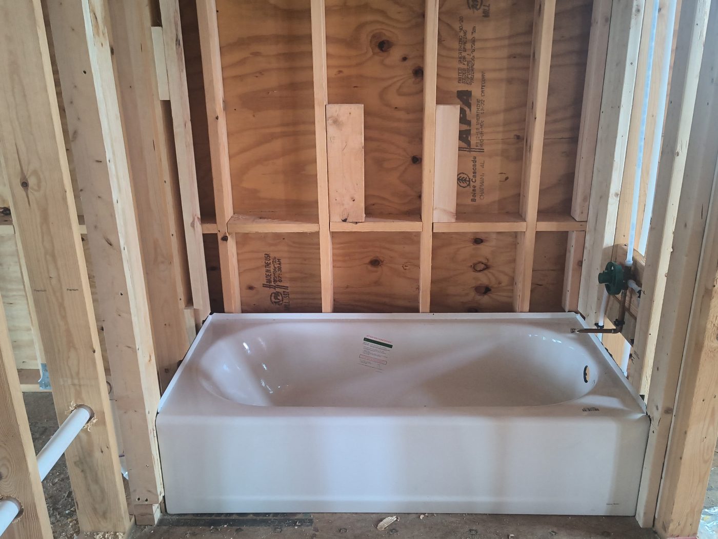Freshly installed bathtub with plumbing stub-outs ready for tile